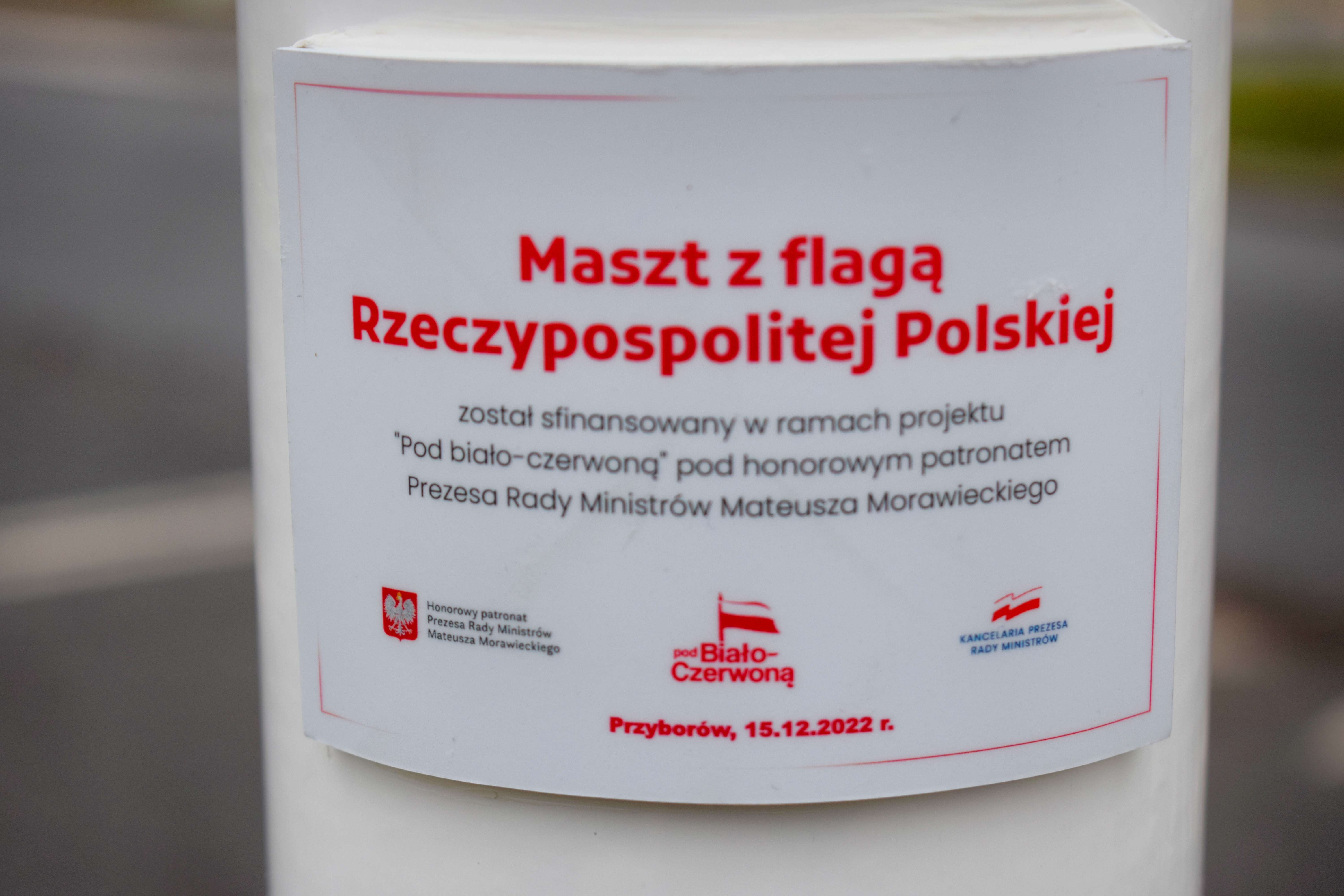tablica z informacją o sfinansowani masztu w ramach projektu „Pod Biało-Czerwoną” pod honorowym patronatem Prezesa Rady Ministrów Mateusza Morawickiego.
